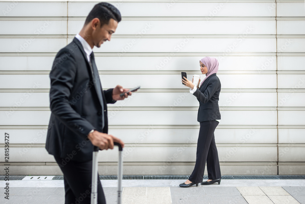 Muslim Business People on their Smartphone while on a coffee break, walking towards each other. Shallow depth of field. Muslim Business People on their Smartphone while on a coffee break, walking towards each other. Shallow depth of field.