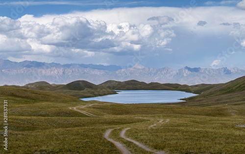 Scenic view of grassy landscape with lake against cloudy sky