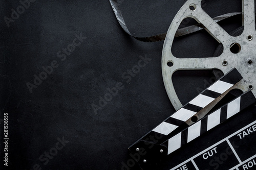 Filmmaker profession with clapperboard and video tape on black background top view copyspace