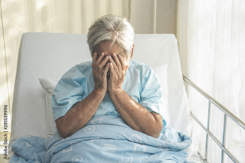 lonely asian elderly female patient lying on the bed in the hospital and looking away outside the window waiting to see her child and her family to visit. lonely asian elderly female patient lying on the bed in the hospital and looking away outside the window waiting to see her child and her family to visit.
