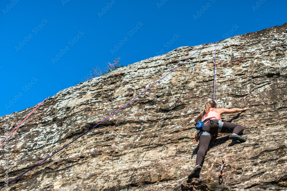 Young woman climbing on rock wall