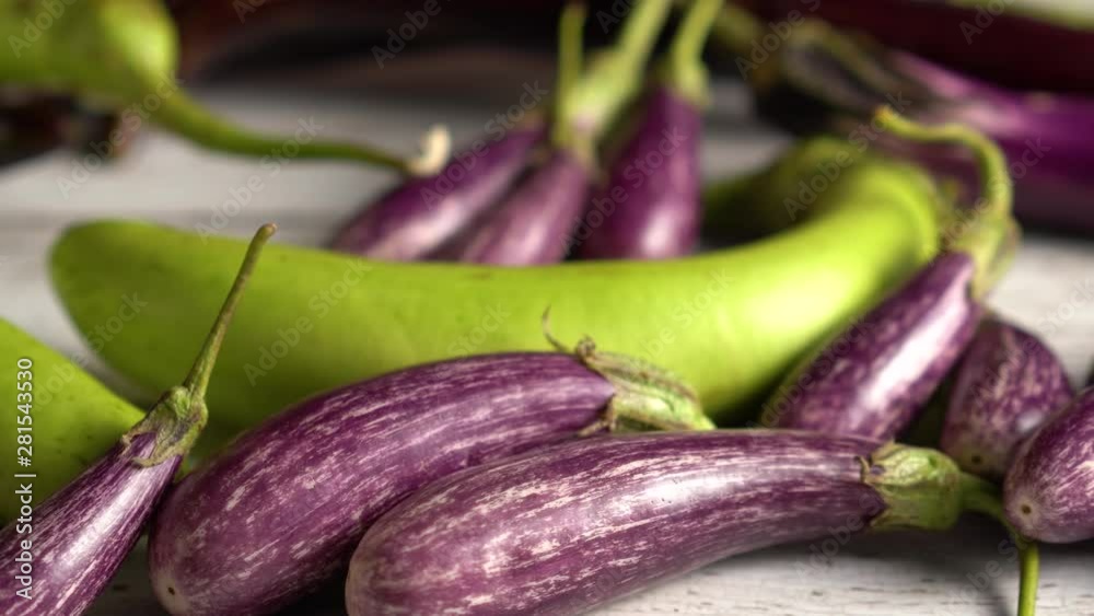Extreme close up of fairy tale eggplants on a wood table, camera sliding to the right.
