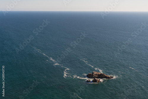 Small rock island isolated on a large ocean landscape