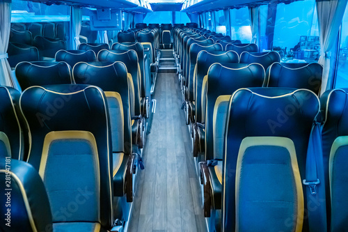 The interior of a modern passenger bus. Intercity bus. Passage between the rows of passenger seats. Seats for passengers. Comfortable long-distance people transportation. Travelling by bus.