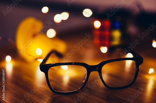 Glasses on desk with lights in the background