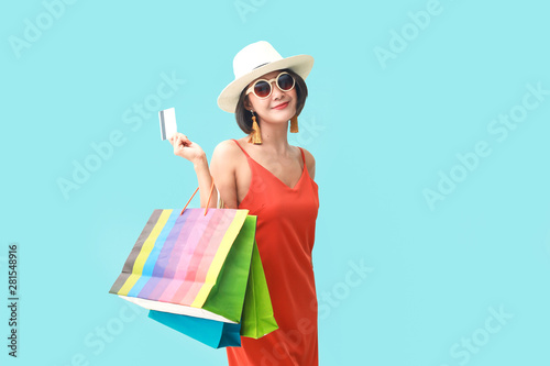 Portrait of asian girl wearing dress and sunglasses holding shopping bags.