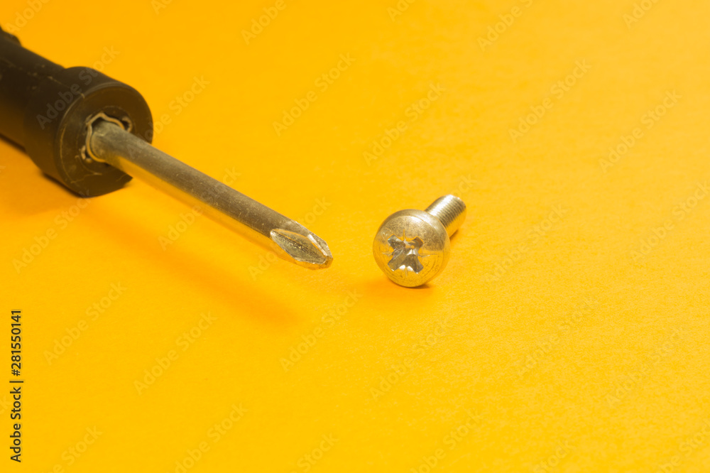 Steel screw on a yellow background Steel screw on a yellow background