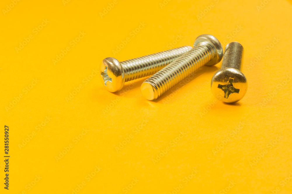Screws on a yellow background. pile of fasteners Screws on a yellow background. pile of fasteners