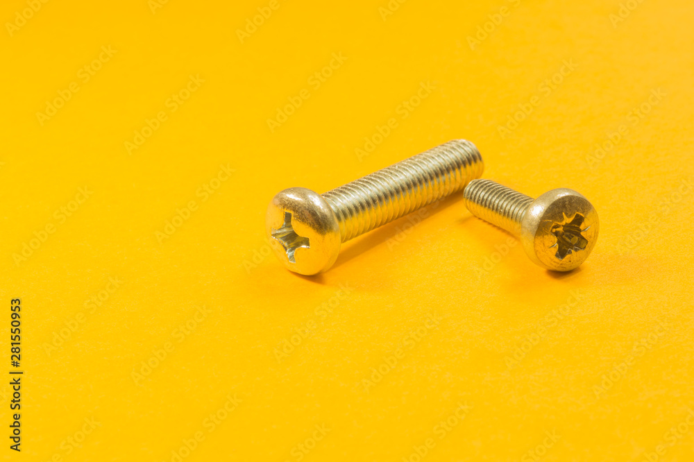 Screws on a yellow background. pile of fasteners