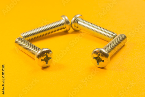 Screws on a yellow background. pile of fasteners