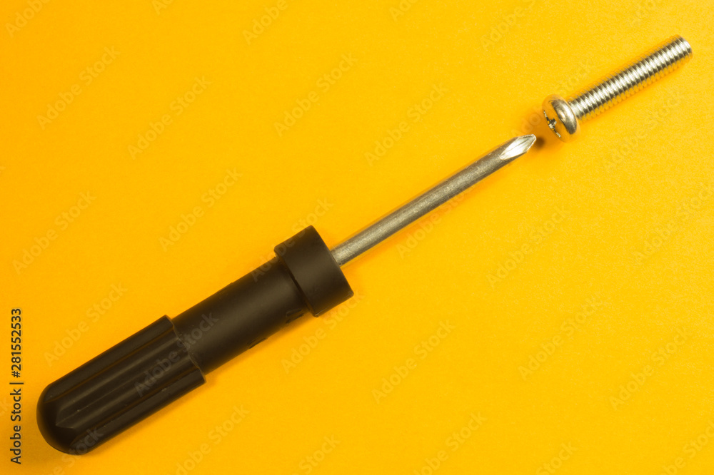 Screws and screwdriver on a yellow background Screws and screwdriver on a yellow background