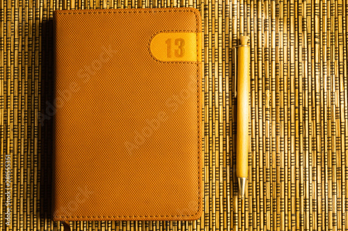 Diary and pen on a wooden bamboo background. notebook and pen top view. number 13