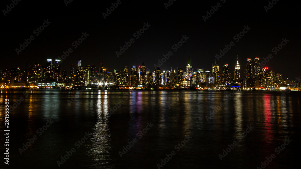 Manhattan skyline at night with reflections off water New York City NYC