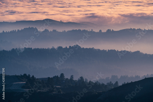Fototapeta Naklejka Na Ścianę i Meble -  Sunset view of layered hills and valleys covered by a sea of clouds in Santa Cruz mountains ; San Francisco bay area, California