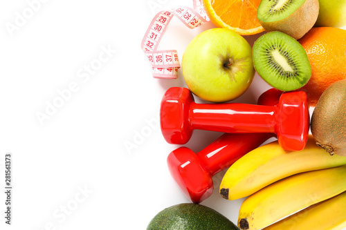 Dumbbells, measuring tape and fruits isolated on white background