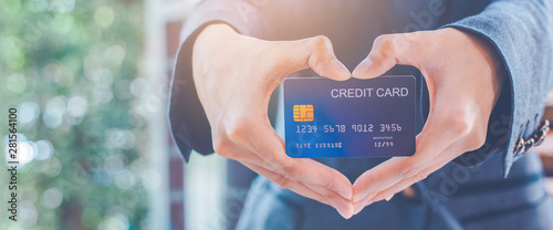 Woman hand are holding a credit card and making a heart-shaped hand.