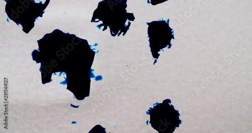 five blue ink dots are floating in a transparent liquid while rapidly growing and expanding themselve. lifelike growing of a bodycell or a disease photo