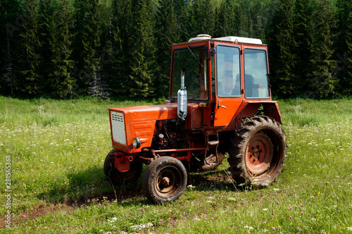 Country road and a tractor in the field on a summer day