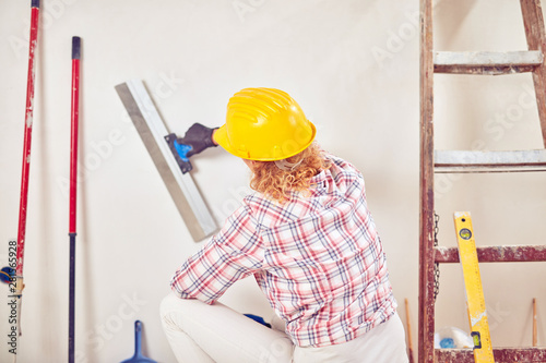 Working woman plastering / painting walls inside the house.