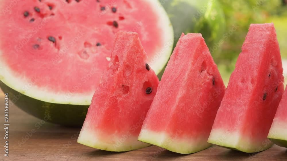 Watermelon slices on the table. Summer refreshment fruits on green foliage background. Camera slide. Watermelon slices on the table. Summer refreshment fruits on green foliage background. Camera slide.