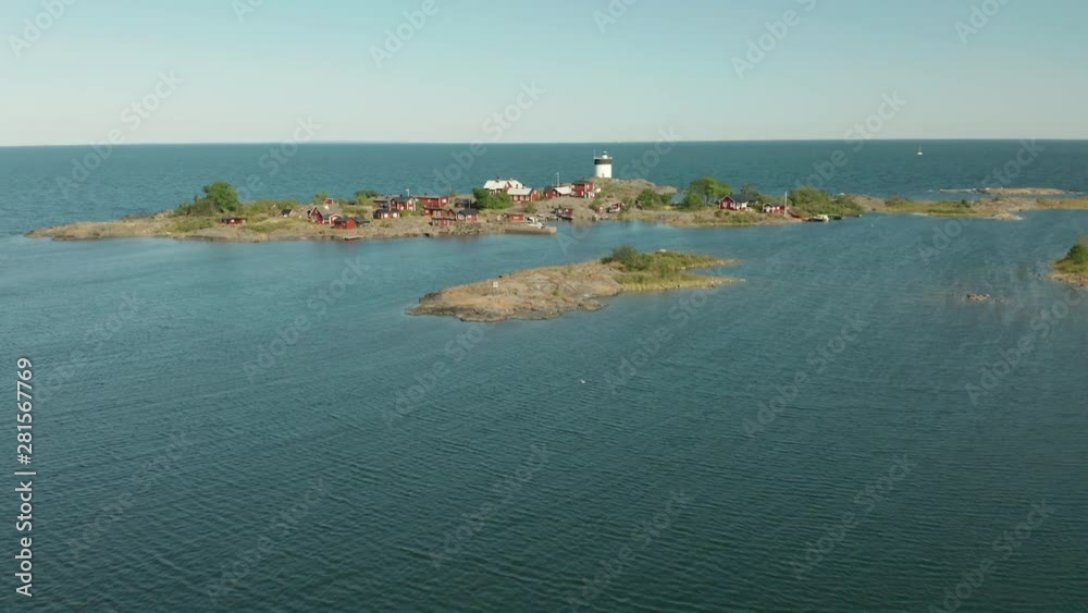 Aerial shot of secluded idyllic island in archipelago. Lighthouse & red cabins, sunny summer day. Aerial shot of secluded idyllic island in archipelago. Lighthouse & red cabins, sunny summer day.
