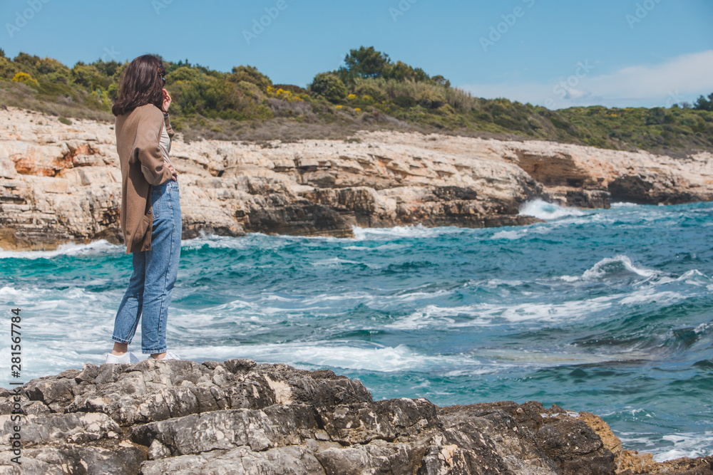 woman standing on cliff enjoying view of the sea. windy weather. sunny day woman standing on cliff enjoying view of the sea. windy weather. sunny day