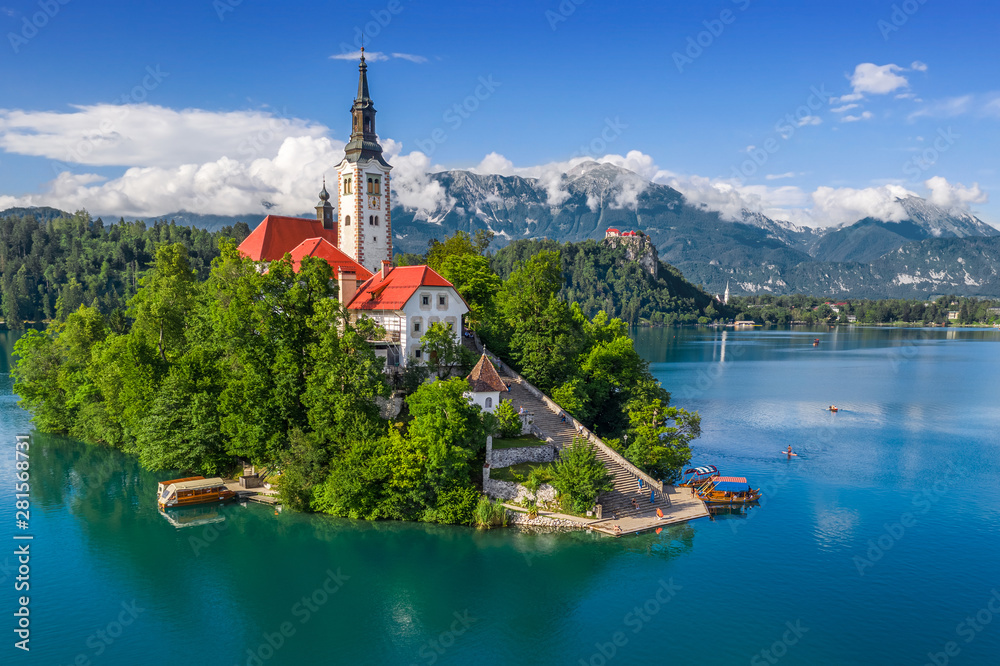 Bled, Slovenia - Aerial view of Lake Bled (Blejsko Jezero) with the Pilgrimage Church of the Assumption of Maria, pletna boats, Bled Castle and Julian Alps on a sunny summer day