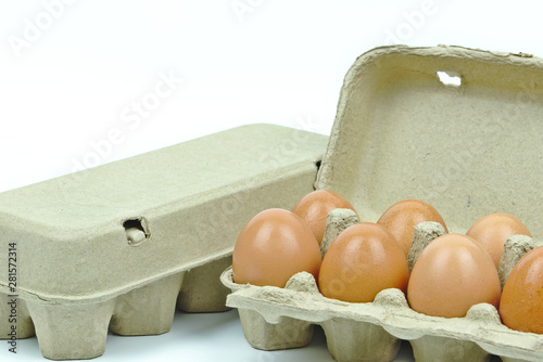 Isolated of seven chicken eggs in brown paper cardboard containers on white background with copy space on the upper left.