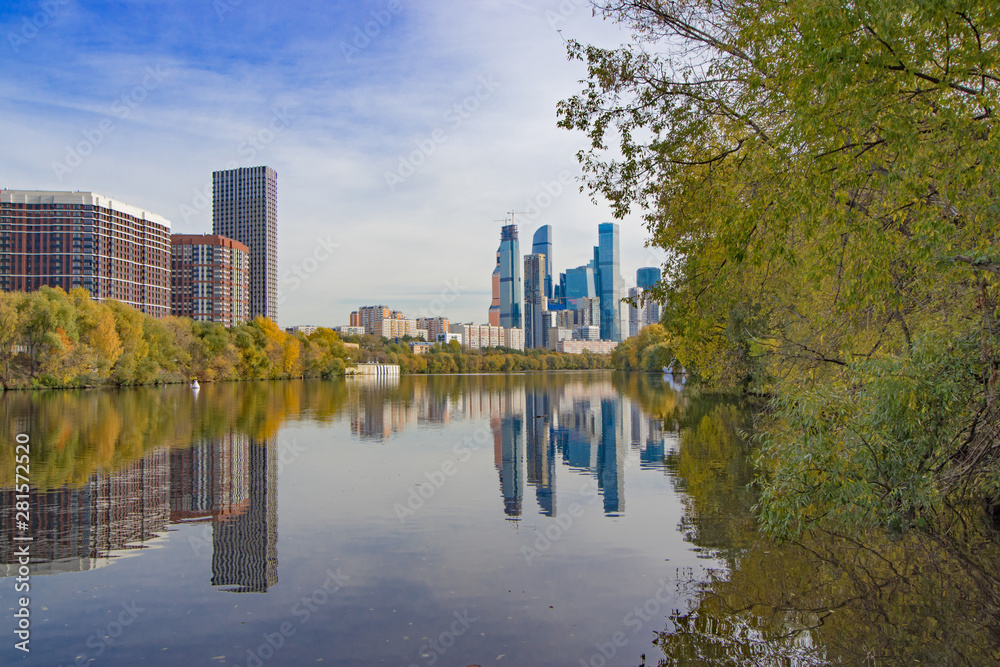 Fototapeta premium Autumn cityscape. Business center Moscow-city and surroundings. View of skyscrapers, new buildings and residential areas of the Russian capital. Reflections in the water of the Moscow River.