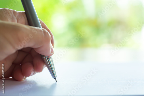 Woman's left Hand holding silver clutch-type pencil, writing letter on white paper texture background, Notebook, Close up & Macro shot, Selective focus, Communication, Stationery concept