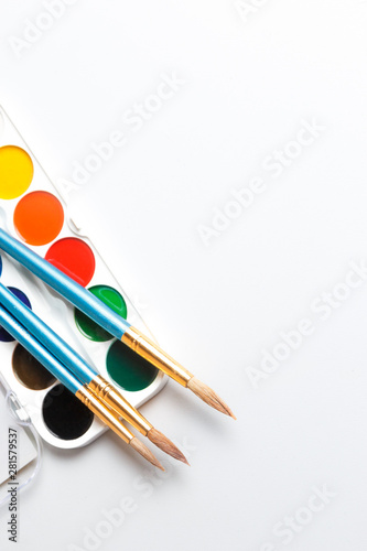 Top view of paintbrushes palette and watercolor paints with white space