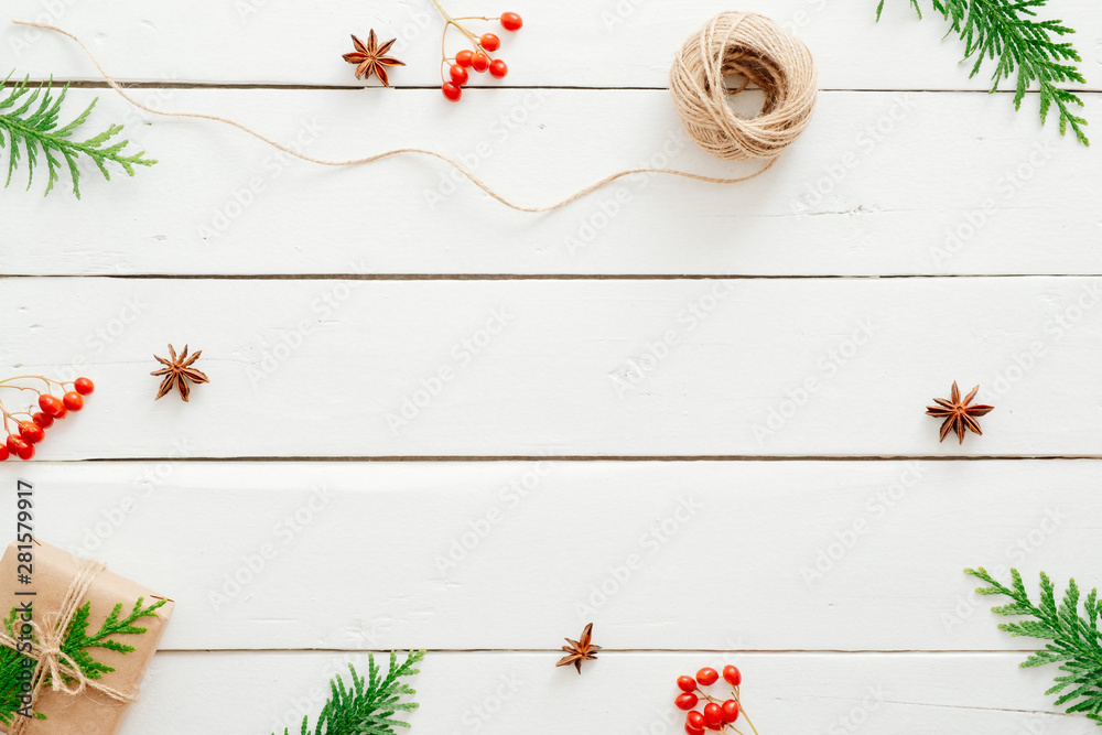 Christmas composition. Frame made of fir tree branches, red berry, presents on wooden white table. Christmas, winter holiday, New year concept. Postcard template mockup.