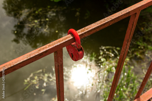 Close-up a red love lock hanging on a metal bridge railing