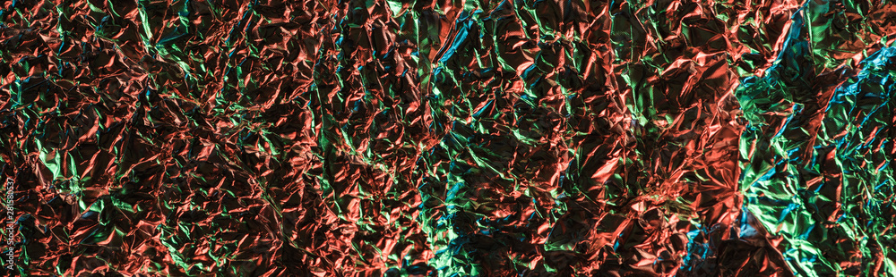 top view of glossy crumpled foil with colorful lighting reflection in darkness isolated on black top view of glossy crumpled foil with colorful lighting reflection in darkness isolated on black