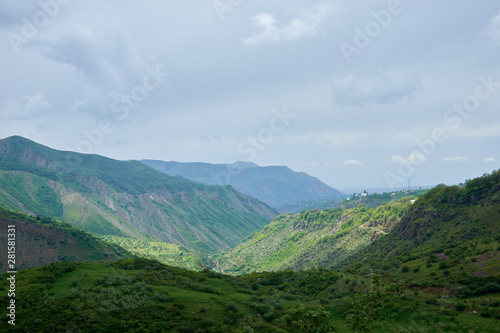 View of a green valley in the mountains on a sunny day with clouds in the sky.