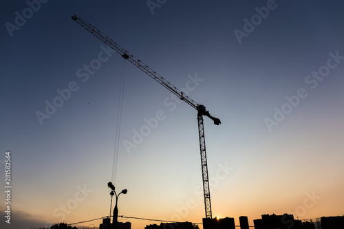 Industrial landscape with silhouette of crane on the sunset background