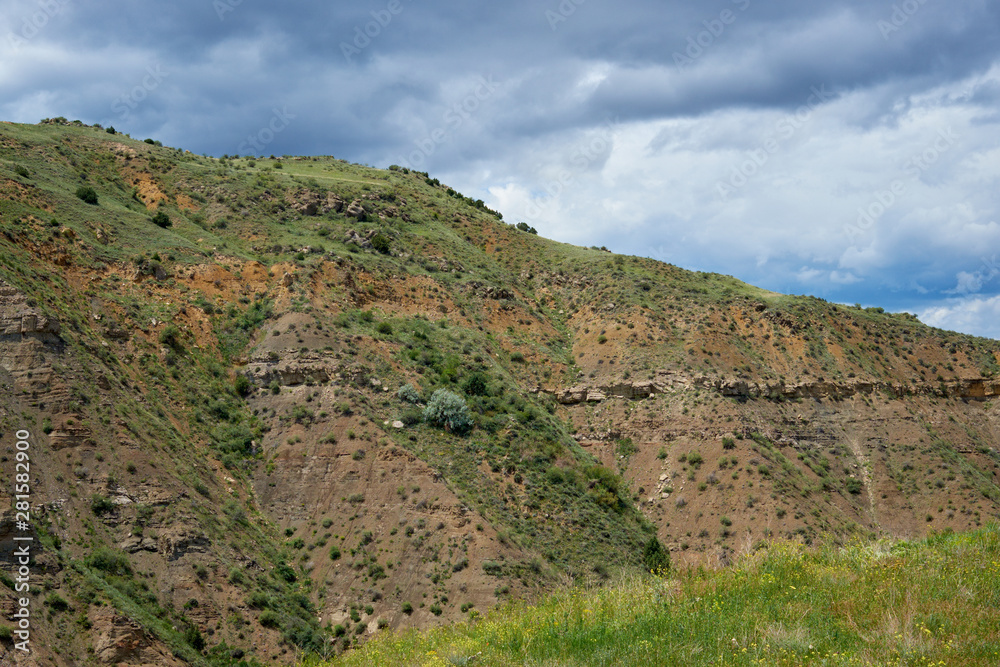 View of a green valley in the mountains on a sunny day with clouds in the sky.