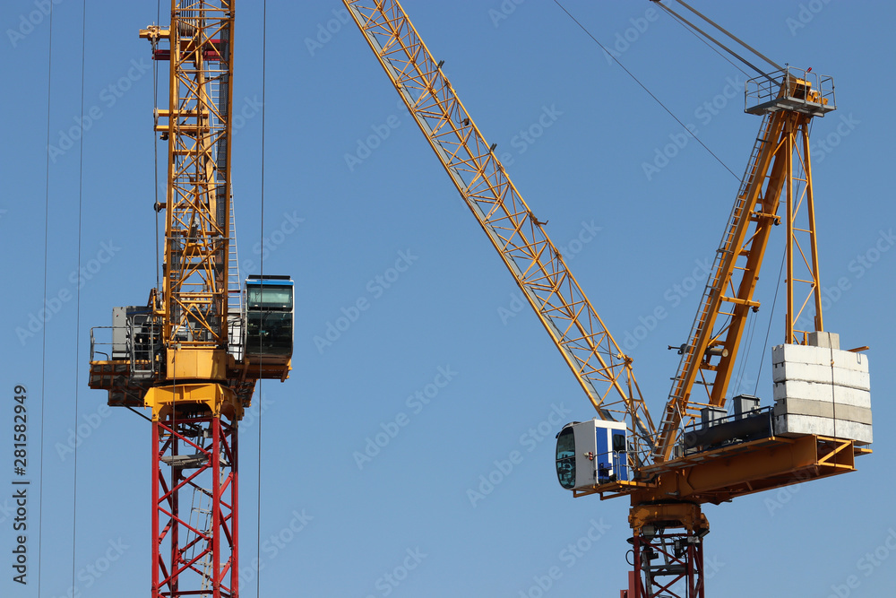 Construction cranes isolated on clear blue sky background. Concept of housing construction or heavy cargo loading work