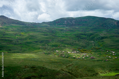 View of a green valley in the mountains on a sunny day with clouds in the sky.