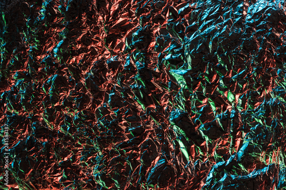 top view of silver crumpled foil with colorful lighting top view of silver crumpled foil with colorful lighting