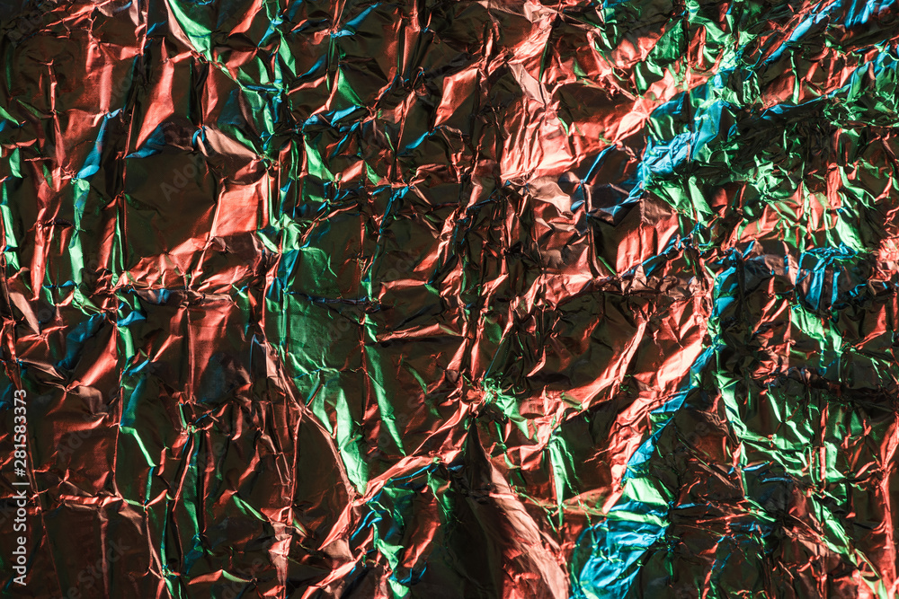 top view of glossy crumpled foil with colorful lighting reflection