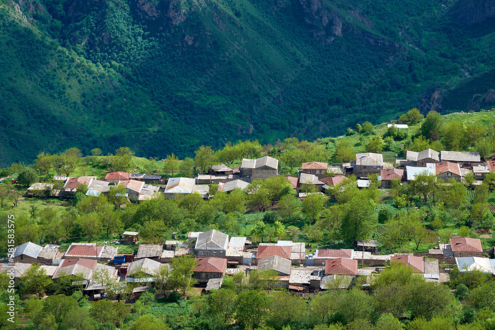 view of the village located in a mountain gorge on a bright sunny day with clouds in the sky.