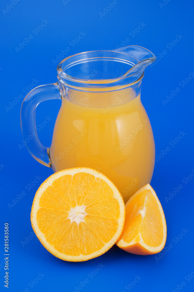 Orange juice in pitcher with orange fruit on blue background Orange juice in pitcher with orange fruit on blue background
