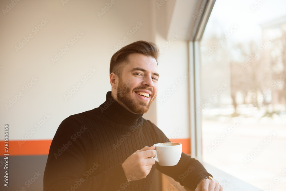 Attractive successful young businessman drinking coffee sitting at cafe table. Attractive successful young businessman drinking coffee sitting at cafe table.