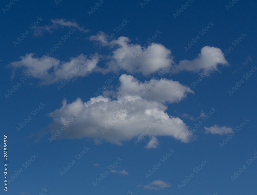 White fluffy clouds in the blue sky on a sunny day White fluffy clouds in the blue sky on a sunny day