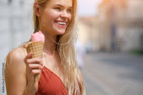 a sunny girl in a summer dress eats ice cream and walks around the streets of the town