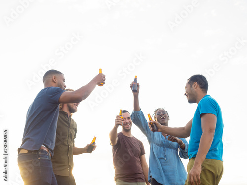 Relaxed people standing with beer bottles. Group of friends relaxing in park during sunset. Leisure concept