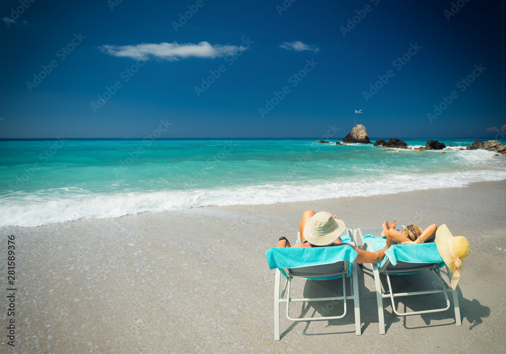Couple on sunbeds relaxing at the beach in Lefkada Couple on sunbeds relaxing at the beach in Lefkada