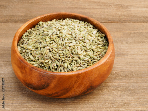 Fennel seeds (Foeniculum vulgare) in a wooden cup on a wooden background
