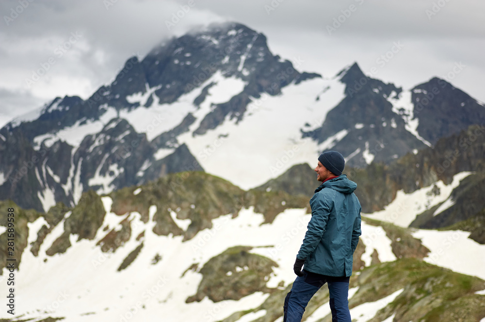 Hiker man stands against mountain top and looks away. Mountain trekking. Travel freedom concept.